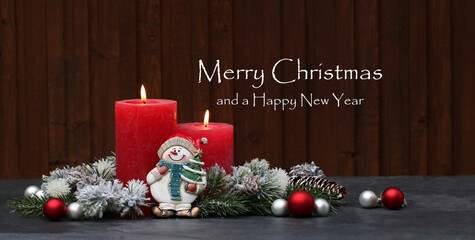 Christmas card: Red burning candles and Christmas decorations against a wooden background with the text Merry Christmas and a Happy New Year.