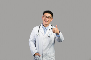 Cheerful middle aged japanese male therapist in white coat and glasses showing thumb up, advice medicine