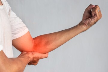 Pain in the elbow joint of Asian young man. Concept of elbow pain, injury, rheumatism or osteoarthritis.