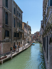 Fototapeta na wymiar Touristen laufen auf einem Fussweg an einem Kanal in der Altstadt von Venedig