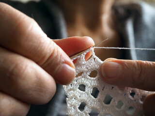 Knitting white crochet lace. Close-up crochet hands.