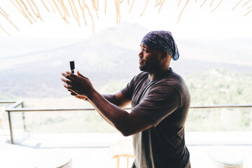 Black man standing and taking selfie on smartphone