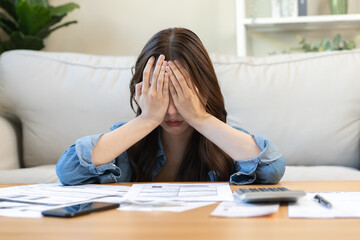 Financial owe asian woman, female hand in cover face, sitting in stressed and confused by calculate expense from invoice or bill, have no money to pay, mortgage or loan. Debt, bankruptcy or bankrupt.