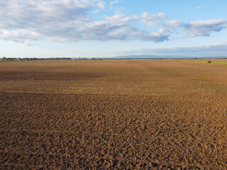 Freshly plowed field ready for seeding and planting in spring.  Brown black soil, aerial drone view.