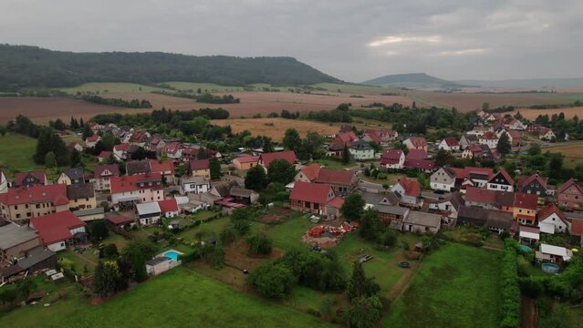 Aer ial view of a German village surrounded by meadows, farmland and forest in Germany.
