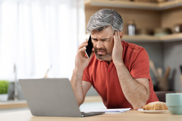 Stressed middle aged businessman working from home, having phone call
