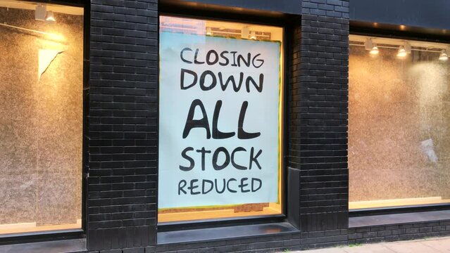 London, UK, December 5th 2022:A shop window closing down sign, all stock reduced. Concept for cost of living, high street retail, business failed, economy and recession. Static shot.
