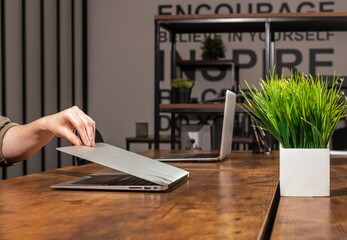 Hand closing lid cover of laptop in office. Ending finishing work day concept