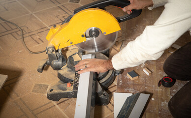Worker cutting part of furniture with cutting machine.