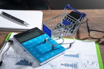 Shopping cart with calculator on business graphs.