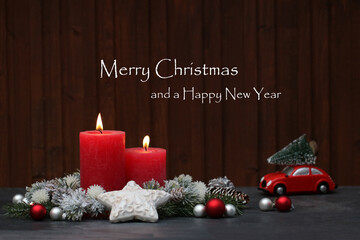 Christmas card: Red burning candles and Christmas decorations against a wooden background with the text Merry Christmas and a Happy New Year.