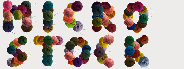 Microstock text made of balls of wool colored yarn for hand knitting on white background. Flat lay, copy space, banner.