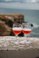 Two glasses of pink champagne on the handicap of the mountains and the sea. Travel and romance. Beautiful landscape. recreation and alcoholic beverages.