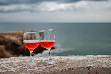 Two glasses of pink champagne on the handicap of the mountains and the sea. Travel and romance. Beautiful landscape. recreation and alcoholic beverages.