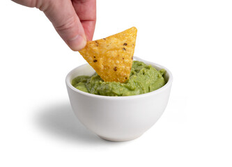 A hand dipping nachos in guacamole sauce