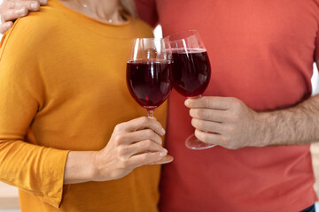 Cropped of loving couple holding glasses with red wine