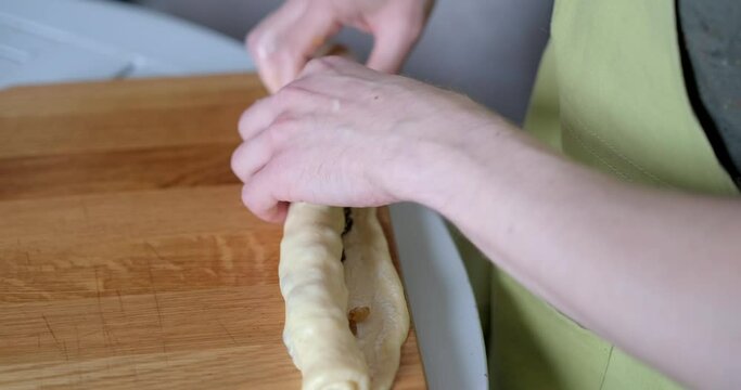 Easter pastry cruffin preparation at home concept. Unrecognizable person folding kneaded dough smeared with butter in a roll. High quality 4k video footage