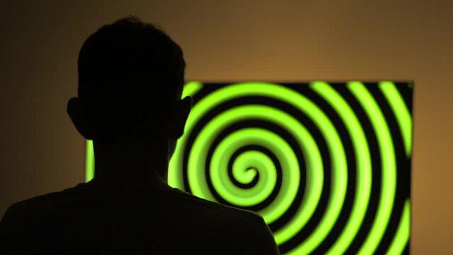 Man watching colorful hypnotising moving spirals