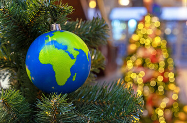 Globe-shaped Christmas ball with countries and continents on the Christmas tree.