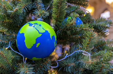 Globe-shaped Christmas ball with countries and continents on the Christmas tree.