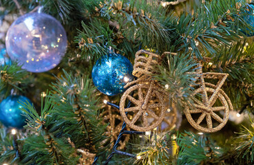 Christmas decoration in the form of a bicycle with golden sparkles on a Christmas tree with a...