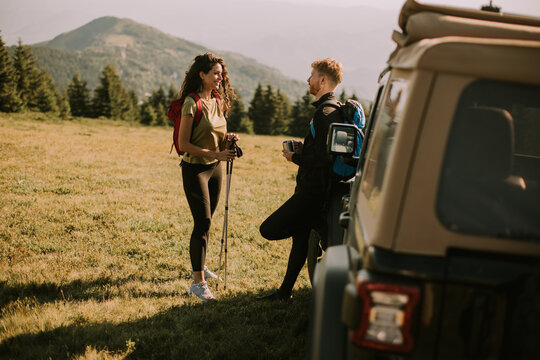 Smiling couple preparing hiking adventure with backpacks by terrain vehicle © BGStock72