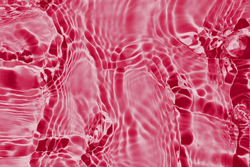Viva magenta color of year 2023. Water surface background. Water texture with splashes, ripples and bubbles