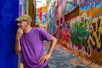 Um homem usando um boné escorado na parede do Beco da Codorna - um ponto turístico da cidade de Goiânia.