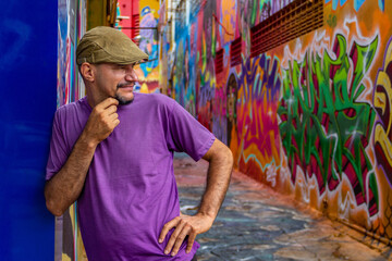 Obraz na płótnie Canvas Um homem usando um boné escorado na parede do Beco da Codorna - um ponto turístico da cidade de Goiânia.