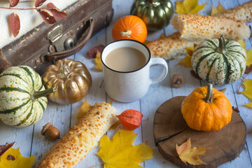 Mug of hot coffee, colorful pumpkins and autumn leaves on a wooden background. Autumn still life.