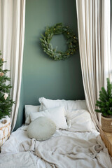 Cozy interior of a small room with a bed and a Christmas wreath