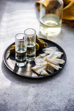 Close-Up of a plate of traditional Ukrainian cured pork fat (salo) with vodka shots and pickled gherkins