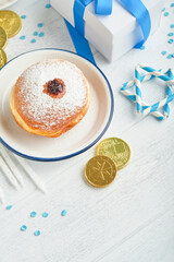 Happy Hanukkah. Hanukkah sweet doughnuts, gift boxes, white candles and chocolate coins on white wooden background. Image and concept of jewish holiday Hanukkah. Top view.