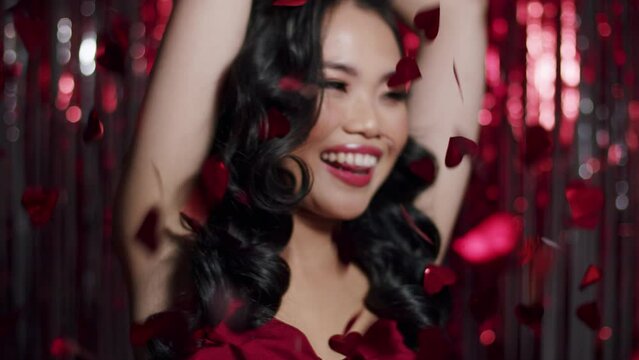 Alluring glamour asian woman dancing among shiny confetti. Valentines. Party. Nerw Year. Celebration. 