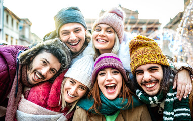 Trendy friends guys and girls taking funny selfie on warm fashion clothes - Happy life style concept with millenial people having fun together out side on winter holidays - Bright sunshine filter