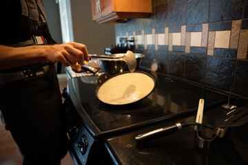 Cooking crepes, flat pancakes in the home kitchen with the laddel