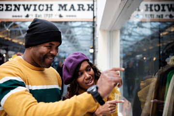 Two smiling deaf friends are looking at a store window in London.