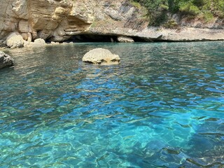Sea azure turquoise water, rocks and coastal cave grotto at summer.