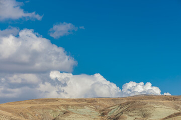 Mountainous terrain and the blue sky with puffy clouds in a sunny day.