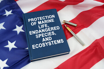 On the US flag lies a pen and a book with the inscription -PROTECTION OF MARINE LIFE, ENDANGERED...