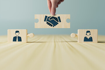 The hand holds wooden wooden blocks with icons of a woman and a man and shaking hands in the act of...
