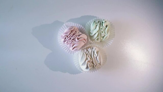 The light moves around the three marshmallows, which casts a shadow on a white