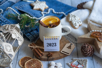 Obraz na płótnie Canvas Calendar for 2023, hot tea with orange, sweets and decorations for the New Year.
