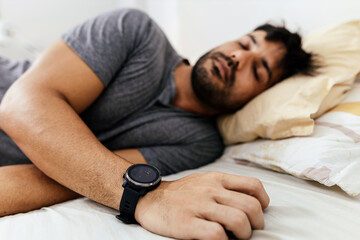 Man with smart watch sleeping in bed at home