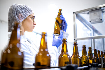 Female factory supervisor controlling beer production in alcohol beverage bottling plant.