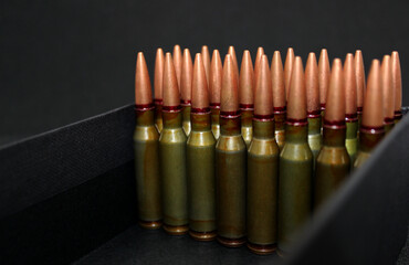 Live ammunition with copper bullets lined up in even rows in a black case closeup stock photo

