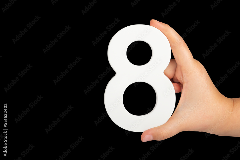 Poster number eight in hand isolated on black background. number 8 in a child's hand on a black background.