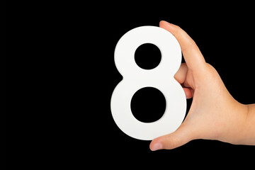 Number eight in hand isolated on black background. Number 8 in a child's hand on a black...