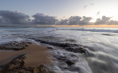 Cloudy view of rocky coast with high tide.