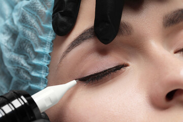 Young woman undergoing procedure of permanent eye makeup, closeup